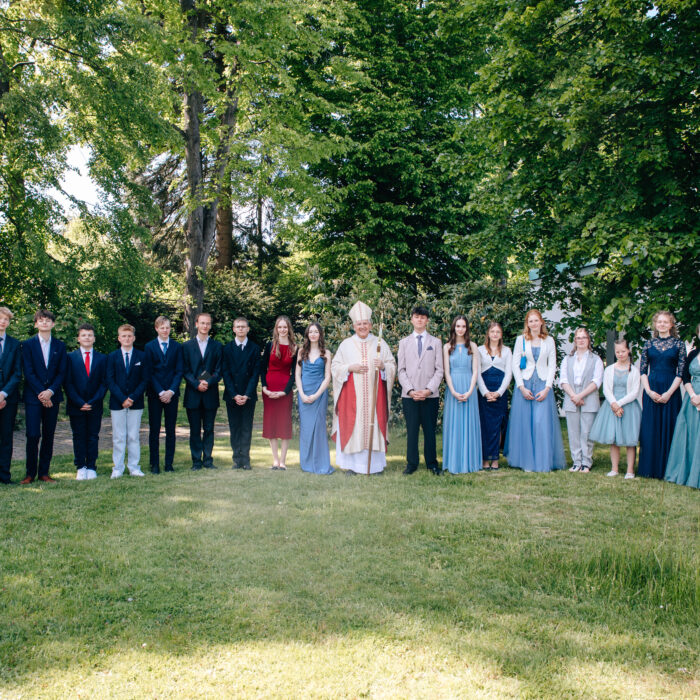 Firmlinge mit Bischof auf einer grünen Wiese