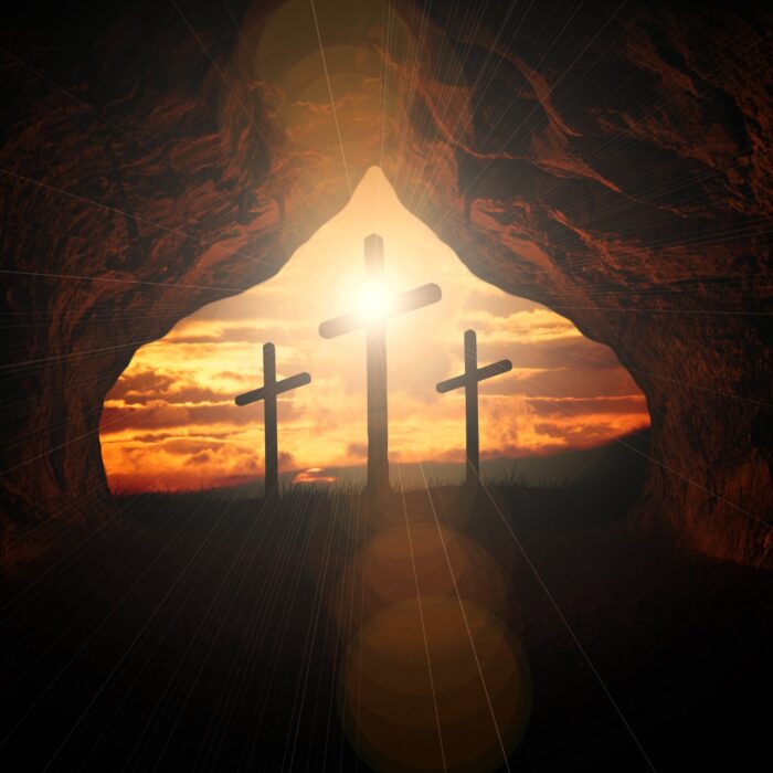 3 Kreuze steht am Ende einer Höhle. Von hinten scheint Sonne die Kreuze an.